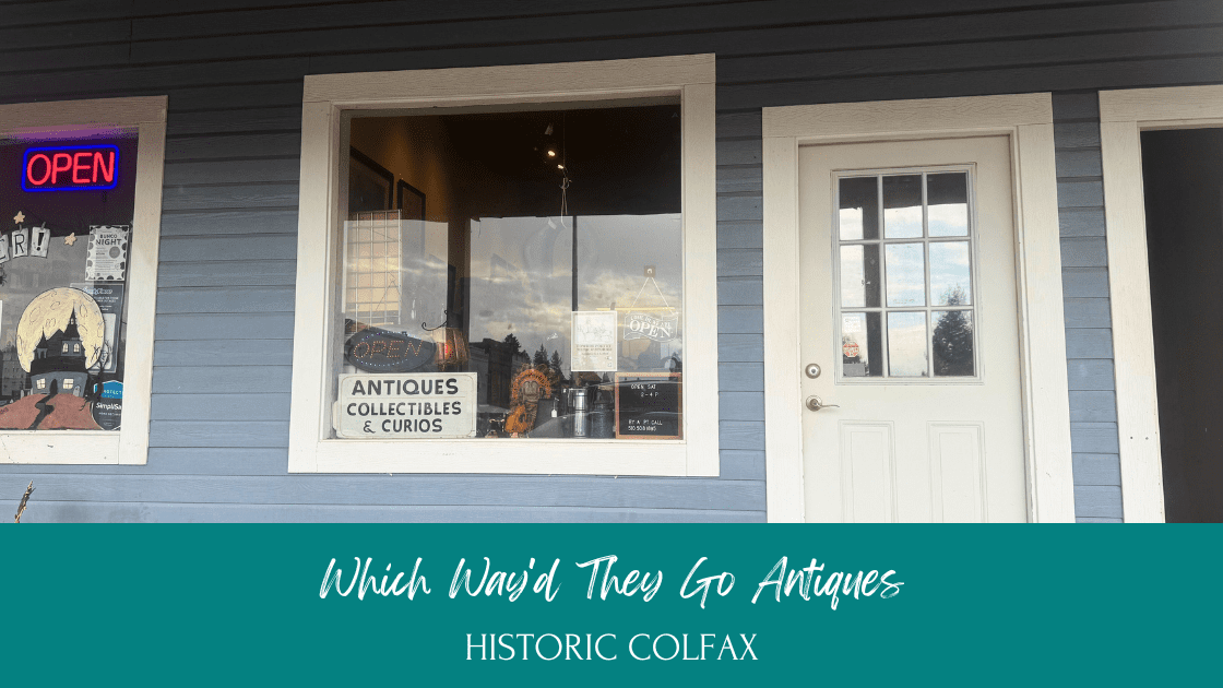Antique display at Which Way'd They Go showing Yosemite landscape art, cowboy sculptures, and blue vintage pottery in downtown Colfax